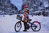 Kind mit Fahrrad und reflektierender Kleidung auf einer verschneiten Straße