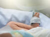 Fuß eines Neugeborenen, an dem ein Pulsoxymetrie-Messgerät angebracht ist