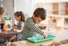 Junge im Grundschulalter steht im Klassenraum an einem Tisch und und arbeitet konzentriert mit seinem Montessori-Material  