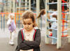 Trauriges Kind auf dem Spielplatz wird von einer Kindergruppe ausgegrenzt
