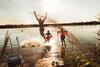 Drei Freunde genießen einen Sommertag und springen von einem Steg in einen See